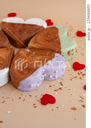 Flat lay greeting card Valentine's Day Delicious fresh variety croissants topped with colorful flavor Ganache. Creation unique heart shape bakery. Puff pastry holiday love gift present idea 129484805