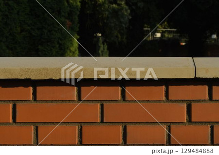 View of the brick base. Brick exterior wall with white finished top with polished white capstone. Brick base. Brick background with polished top with headstone. Building and construction concept. View of the brick base. Brick exterior wall with white finished top with polished white capstone. Brick base. Brick background with polished top with headstone. Building and construction concept. 129484888