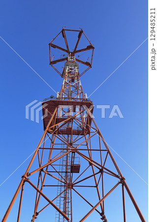 The communication tower stands against the sky with a bottom-up view. Close-up 129485211