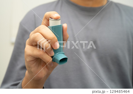 Asthma and chronic obstructive pulmonary disease COPD, Asian young man using metered dose inhaler MDI. 129485464