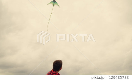 Carefree kids launching a kite, Imagination takes flight, Simple joys of childhood, Boys in matching shirts play, Green kite against cloudy sky, Childhood memories in the meadow, Adventures in an open 129485788