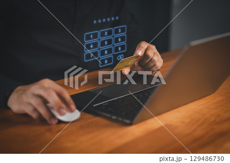 Man entering PIN code while holding a credit card, with virtual numeric keypad on screen. Concept of secure online payment, cybersecurity, internet banking, and digital transaction authentication. Man entering PIN code while holding a credit card, with virtual numeric keypad on screen. Concept of secure online payment, cybersecurity, internet banking, and digital transaction authentication. 129486730