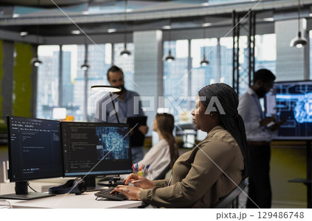 System administrator in tech startup uses AI on PC to optimize performance and forecast issues. African american woman in office training machine learning models using computer System administrator in tech startup uses AI on PC to optimize performance and forecast issues. African american woman in office training machine learning models using computer 129486748