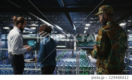 Military technician in data center monitoring warfare drone telemetry on laptop dashboard. IT specialist in army server room using tactical interface on notebook to support aerial operations 129486812