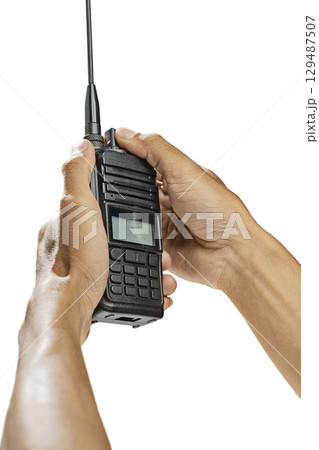 Closeup view of a human hand holding a black walkie talkie radio communication device isolated over a white background 129487507