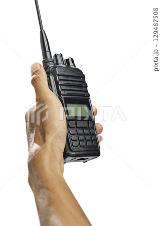 Closeup view of a human hand holding a black walkie talkie radio communication device isolated over a white background Closeup view of a human hand holding a black walkie talkie radio communication device isolated over a white background 129487508