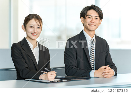 机に並ぶスーツ姿のビジネスマンとビジネスウーマン(面接官,企業説明会) 机に並ぶスーツ姿のビジネスマンとビジネスウーマン(面接官,企業説明会) 129487586