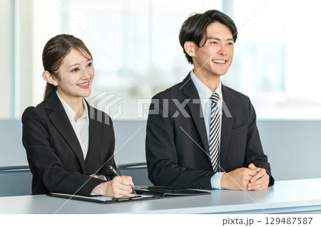 机に並ぶスーツ姿のビジネスマンとビジネスウーマン（面接官,企業説明会） 129487587