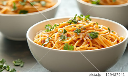 Delicious Pasta Dish with Fresh Herbs in White Bowls on Table Delicious Pasta Dish with Fresh Herbs in White Bowls on Table 129487941