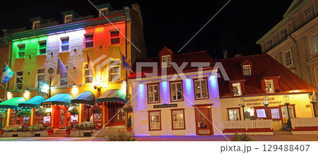 Tourists enjoying walking in Old Quebec City streets, including colourful illuminated restaurants 129488407