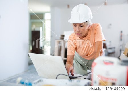 Woman using laptop in apartment under reconstruction Woman using laptop in apartment under reconstruction 129489090