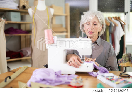 woman dressmaker sews on a machine in a workshop 129489208
