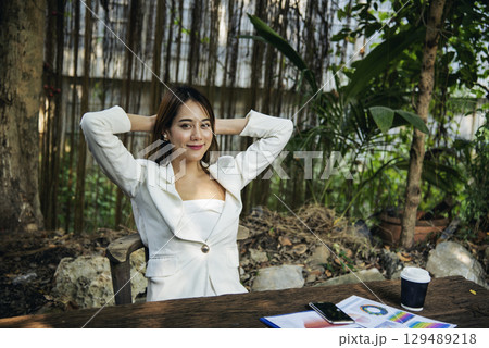 Woman streching arm raised sitting incorrect position home office desk. Back side of young asian woman tired from work body stress back pain office syndrome. Female work from home new normal concept 129489218