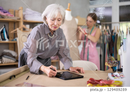 Mature Fashion Designer Drawing Mockup On Tablet Mature Fashion Designer Drawing Mockup On Tablet 129489289