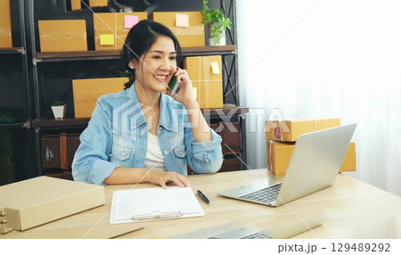 Online seller entrepreneur young asian woman using phone calling, checking online order. Woman calling check goods stock, delivery package shipping. Asian woman startup small business at home office Online seller entrepreneur young asian woman using phone calling, checking online order. Woman calling check goods stock, delivery package shipping. Asian woman startup small business at home office 129489292
