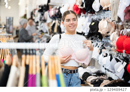 Young woman choosing pretty bra in underwear store Young woman choosing pretty bra in underwear store 129489427