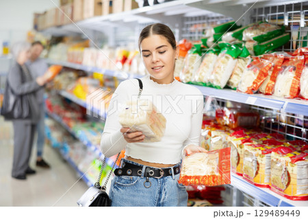 Young woman in supermarket buys daily groceries, pasta Chinese noodles 129489449