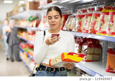 Young woman in supermarket photo package pasta Chinese noodles 129489467