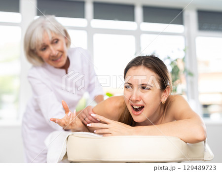 Female client experiencing discomfort during back massage session 129489723