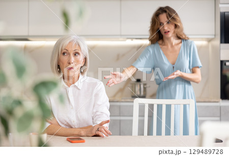 Offended senior woman listening her daughter swearing Offended senior woman listening her daughter swearing 129489728