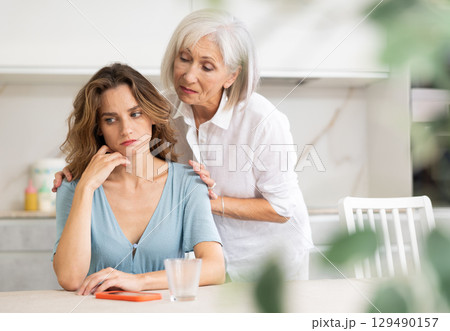 Elderly woman quarrels with couple in kitchen Elderly woman quarrels with couple in kitchen 129490157