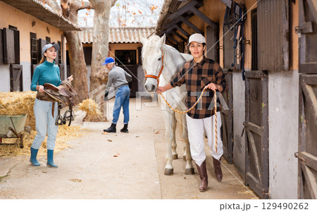 Women ranchers preparing white horse for ride 129490262