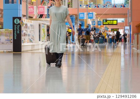 空港で手荷物を引いて歩く女性　旅行客　観光客 129491206