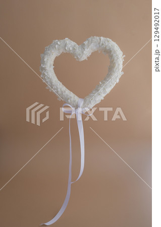 Heart made of white lilac flowers levitating on pastel beige background. Still life romantic composition of Valentines day holiday copy space for your text invitation greeting card 129492017