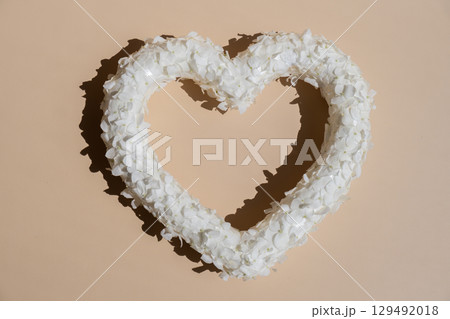 Heart made of white lilac flowers on pastel beige background. Still life romantic composition of Valentines day holiday copy space for your text invitation greeting card 129492018
