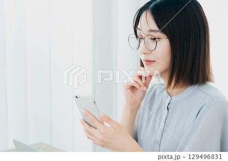 オフィスでスマホを見るビジネスウーマン オフィスでスマホを見るビジネスウーマン 129496831
