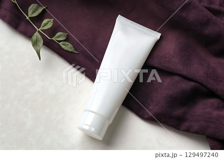 Minimalist White Tube on Purple Fabric with Green Leaf for Skincare, Beauty, or Product Display 129497240