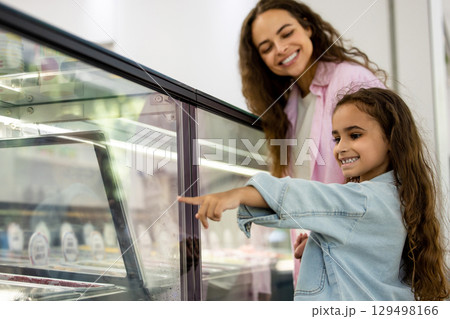 Smiling mother and daughter choosing ice cream in modern dessert shop 129498166