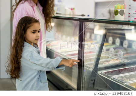 Woman and little girl with long curly hair choosing frozen desserts 129498167