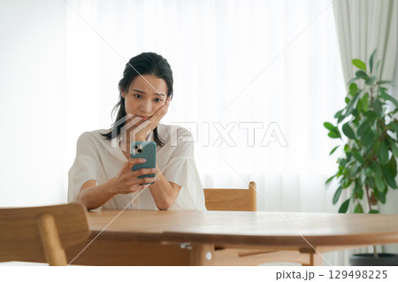 スマホを使う落ち込んだ表情の女性 スマホを使う落ち込んだ表情の女性 129498225