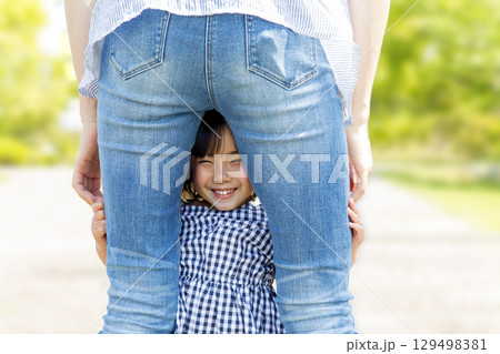 お母さんの後ろ姿の股から覗く笑顔の幼い女の子 129498381