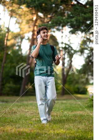 Dark-haired teen smiling and talking on the phone Dark-haired teen smiling and talking on the phone 129498451