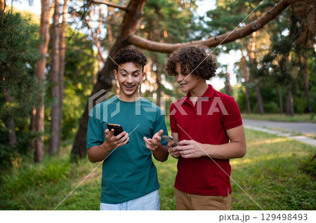 Teens with phones in hands spending time together in the park 129498493