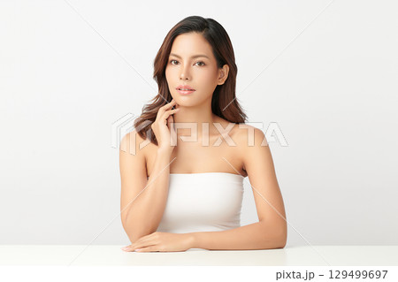 A beautiful young Asian woman with clean, fresh skin against a white background. Skincare, facial treatment, cosmetology, beauty, and spa. An elegant portrait of an Asian woman. 129499697