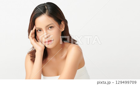 A beautiful young Asian woman with clean, fresh skin against a white background. Skincare, facial treatment, cosmetology, beauty, and spa. An elegant portrait of an Asian woman. 129499709