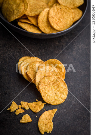 Crispy potato chips on black table. 129500647