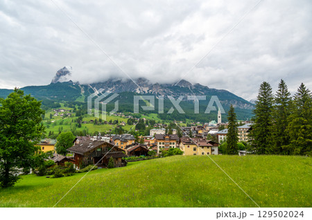 A panoramic view of the picturesque town of Cortina d'Ampezzo, nestled in the heart of the Dolomites. Majestic mountains rise in the background, offering a stunning natural backdrop. 129502024