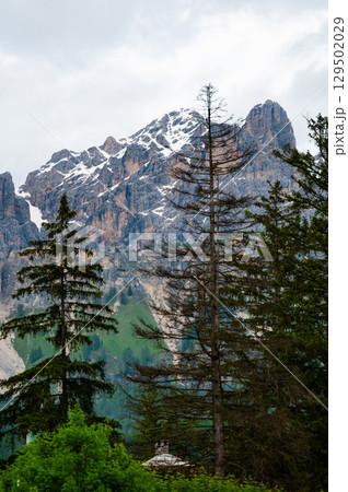 A panoramic view of the picturesque town of Cortina d'Ampezzo, nestled in the heart of the Dolomites. Majestic mountains rise in the background, offering a stunning natural backdrop. A panoramic view of the picturesque town of Cortina d'Ampezzo, nestled in the heart of the Dolomites. Majestic mountains rise in the background, offering a stunning natural backdrop. 129502029