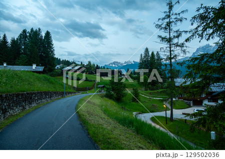 A panoramic view of the picturesque town of Cortina d'Ampezzo, nestled in the heart of the Dolomites. Majestic mountains rise in the background, offering a stunning natural backdrop. A panoramic view of the picturesque town of Cortina d'Ampezzo, nestled in the heart of the Dolomites. Majestic mountains rise in the background, offering a stunning natural backdrop. 129502036