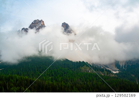 Mountain trail in the Dolomites (Dolomiti, Dolomiten), Italy, leading to Lago Sorapis. The path winds along rocky slopes with stunning views of valleys, forests, and peaks Mountain trail in the Dolomites (Dolomiti, Dolomiten), Italy, leading to Lago Sorapis. The path winds along rocky slopes with stunning views of valleys, forests, and peaks 129502169