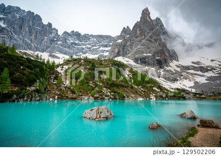 Panoramic view of Lago Sorapis in the Dolomites (Dolomiti, Dolomiten), Italy. The turquoise lake is surrounded by towering cliffs and mountains, a popular spot for hikers and nature lovers Panoramic view of Lago Sorapis in the Dolomites (Dolomiti, Dolomiten), Italy. The turquoise lake is surrounded by towering cliffs and mountains, a popular spot for hikers and nature lovers 129502206