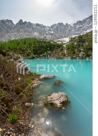 Panoramic view of Lago Sorapis in the Dolomites (Dolomiti, Dolomiten), Italy. The turquoise lake is surrounded by towering cliffs and mountains, a popular spot for hikers and nature lovers 129502211