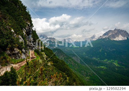 Breathtaking view of forests, mountains, and valleys in the Italian Dolomites (Dolomiti, Dolomiten). Captured from a scenic trail along a rocky ledge. Stunning alpine nature Breathtaking view of forests, mountains, and valleys in the Italian Dolomites (Dolomiti, Dolomiten). Captured from a scenic trail along a rocky ledge. Stunning alpine nature 129502294