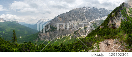 Breathtaking view of forests, mountains, and valleys in the Italian Dolomites (Dolomiti, Dolomiten). Captured from a scenic trail along a rocky ledge. Stunning alpine nature Breathtaking view of forests, mountains, and valleys in the Italian Dolomites (Dolomiti, Dolomiten). Captured from a scenic trail along a rocky ledge. Stunning alpine nature 129502302