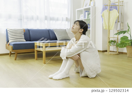 リビングのフローリングに座って靴下を足先を触る若い女性 リビングのフローリングに座って靴下を足先を触る若い女性 129502314