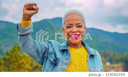 Black mature woman outdoors with raised fist of empowerment, strength and women solidarity, International Womens Day, Black History Month concept Black mature woman outdoors with raised fist of empowerment, strength and women solidarity, International Womens Day, Black History Month concept 129502354